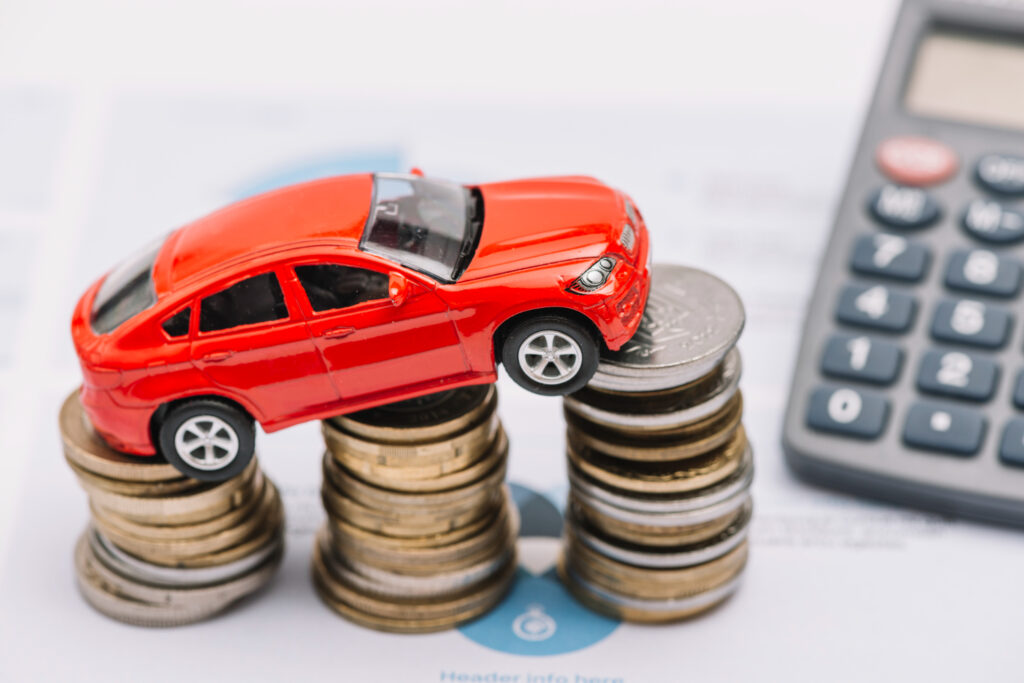 A toy car placed on a stack of coins, signifying car financing.