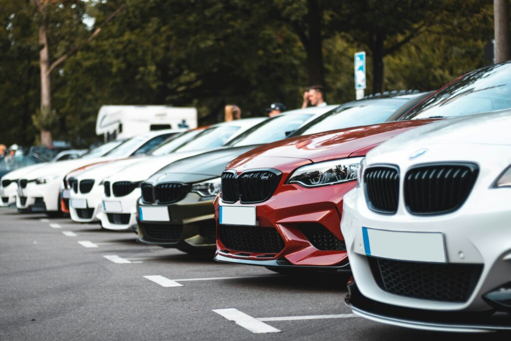 A lineup of BMW cars parked in a row at outdoor dealership lot.