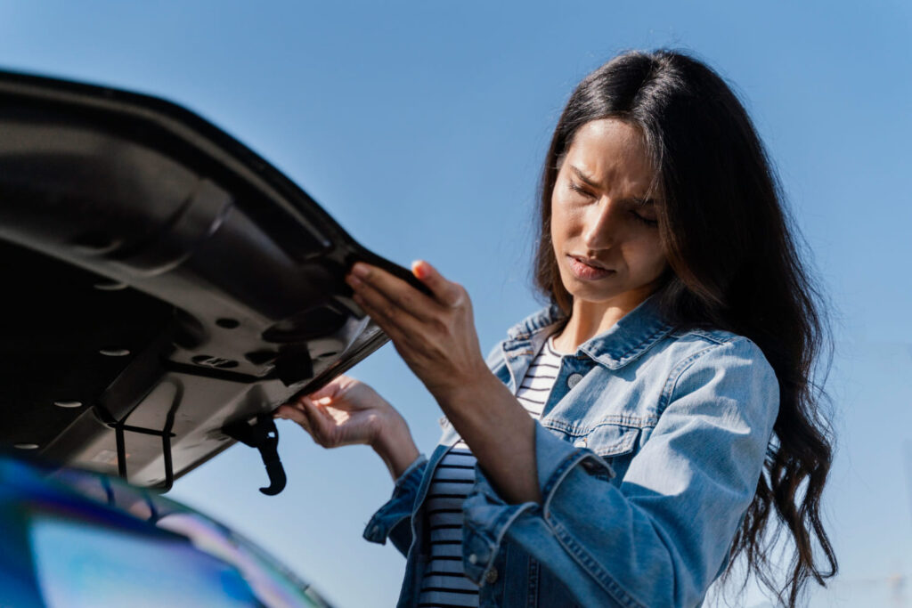 A lady is checking the car bonnet. 