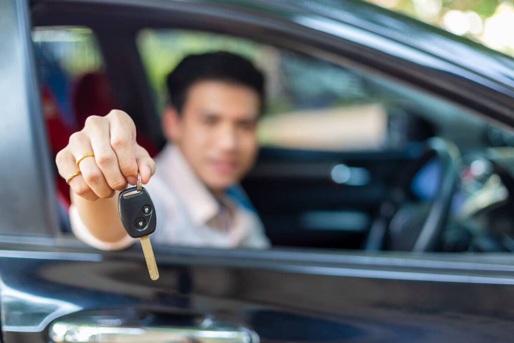 A man is showing his car key from the car.