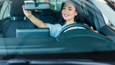 A woman adjusts rear-view mirror.