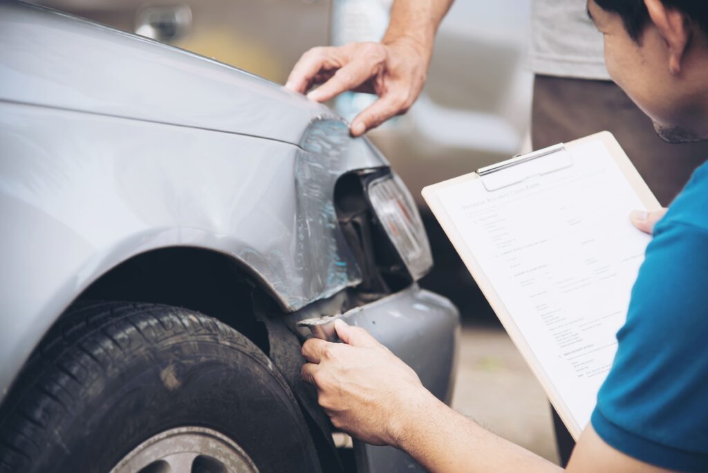 An insurance agent inspecting a car that was involved in an accident.