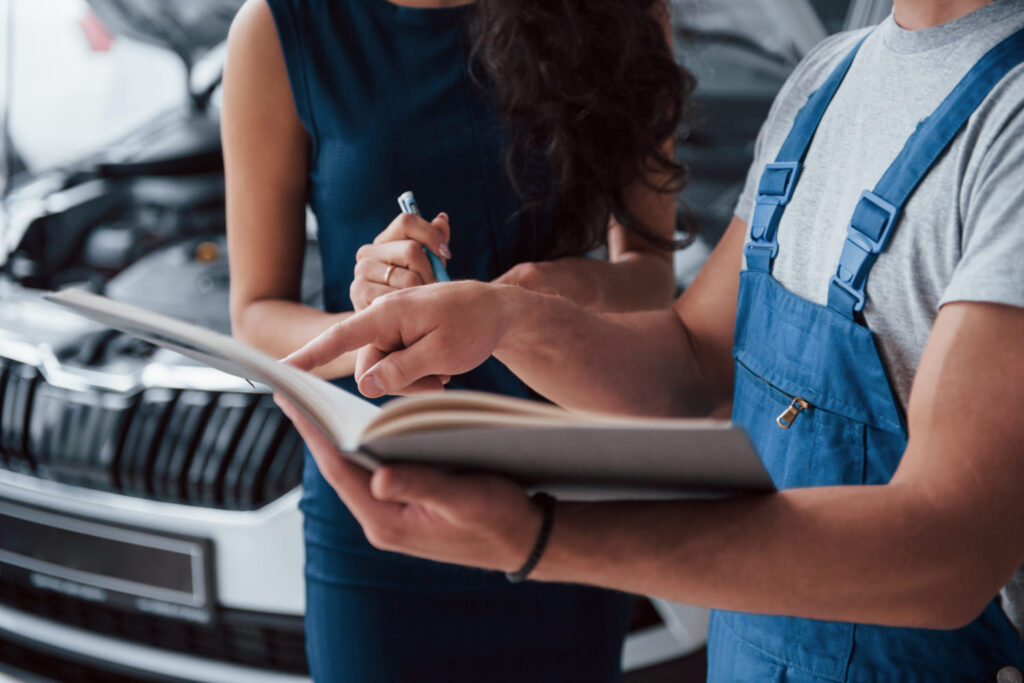 A mechanic is showing car information to a customer. 