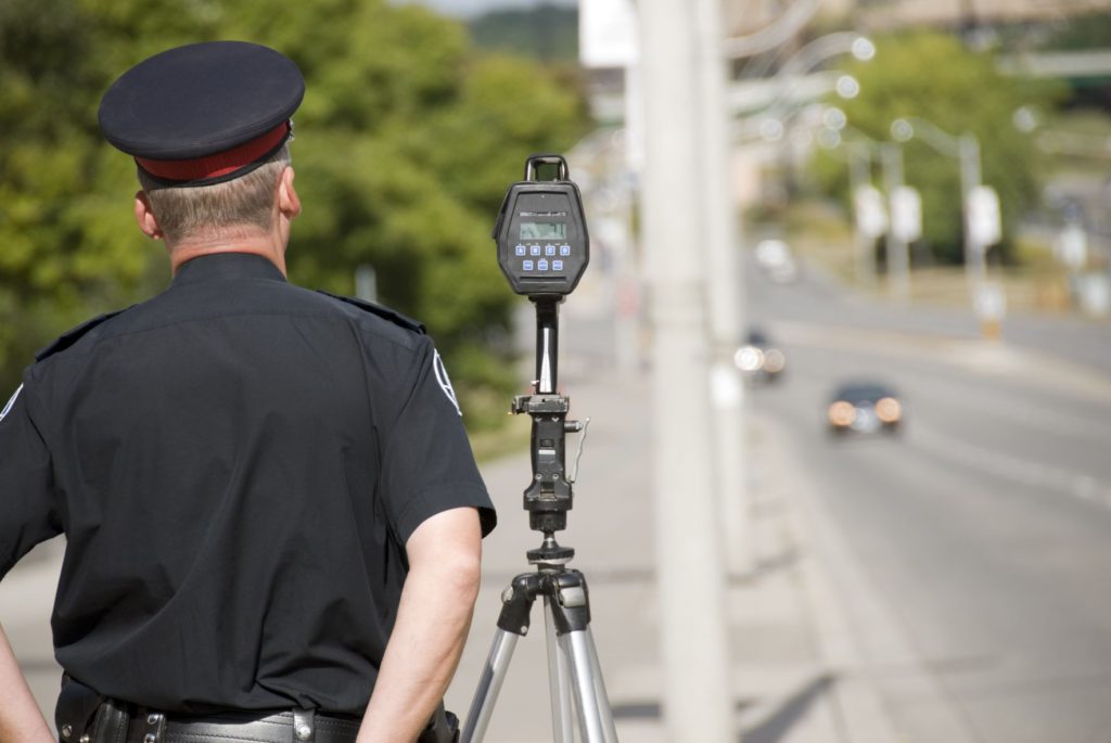 Speeding can cause car accidents. Policeman and speedometer