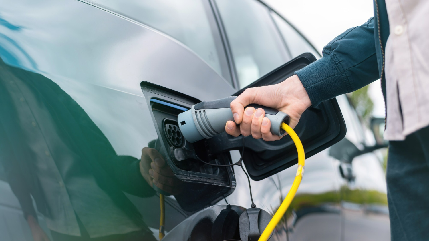 A person plugging an EV charger into an EV