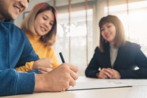 All you need to know about early settlement for car loans in Singapore Man woman signing document